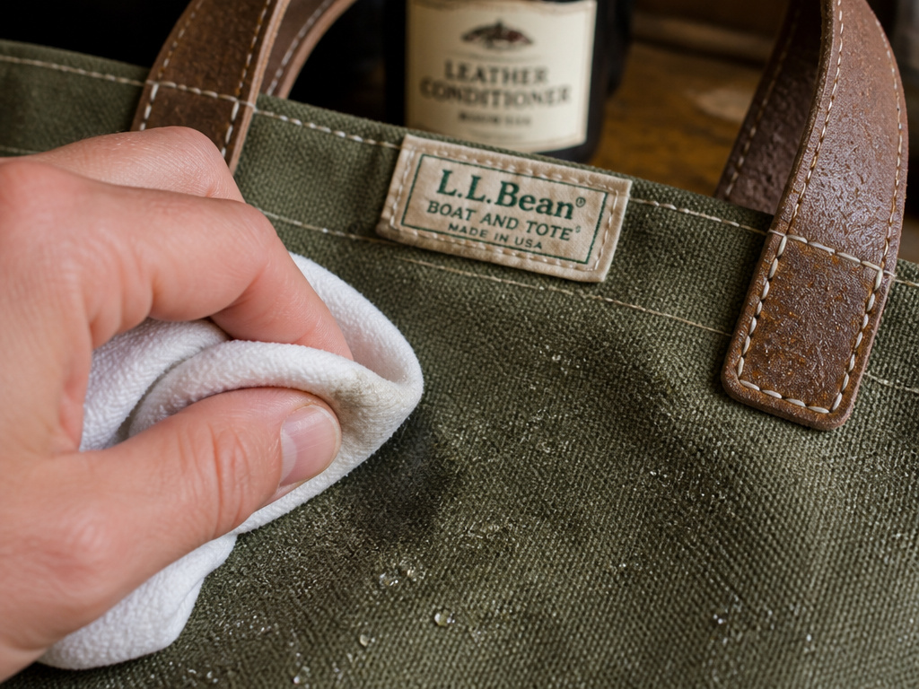 Spot cleaning a waxed LL Bean tote bag next to leather care products